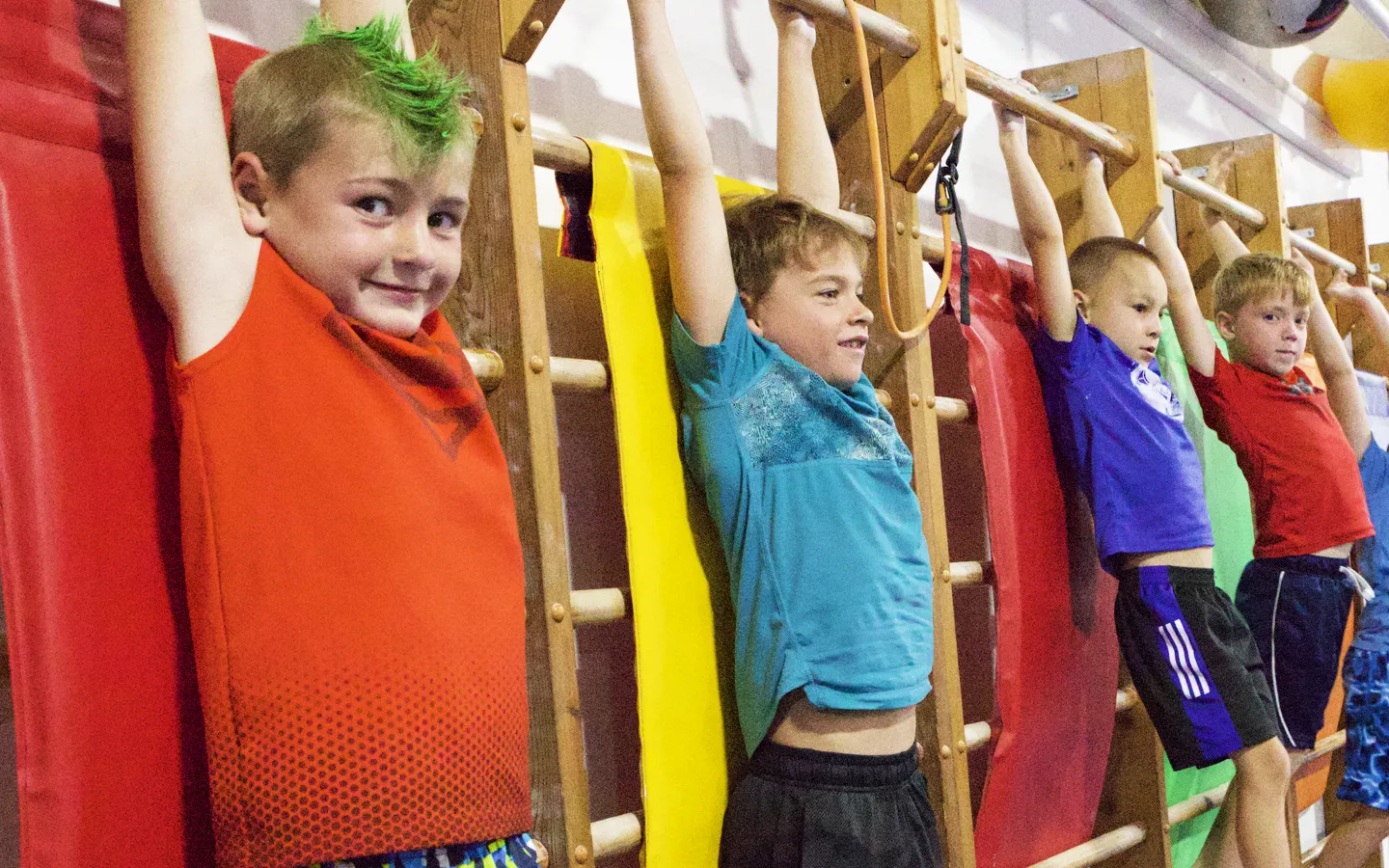 Four boys hanging from the wall bars during a Tiger Boys class