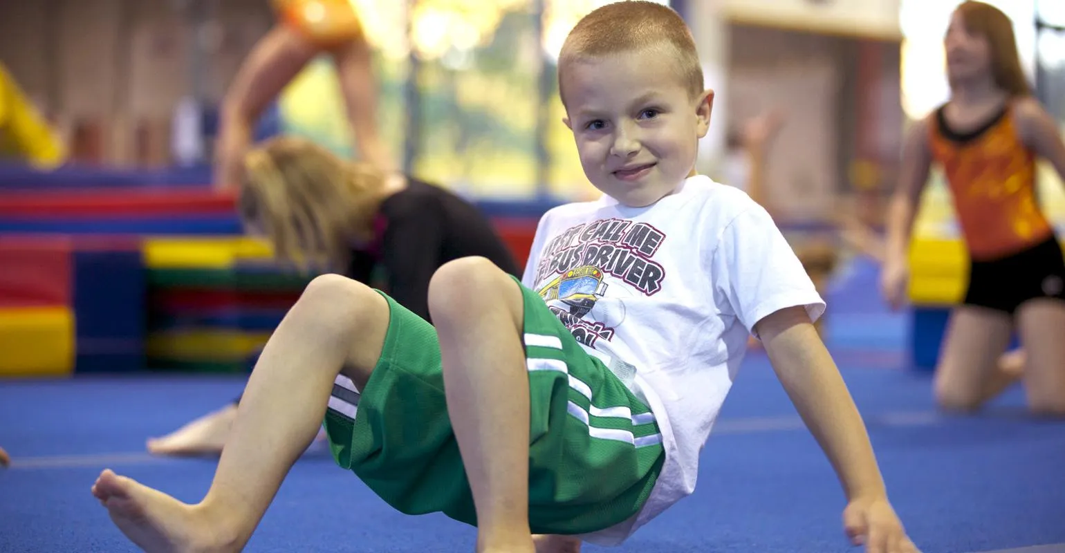 A boy holding a V-sit on the floor during class