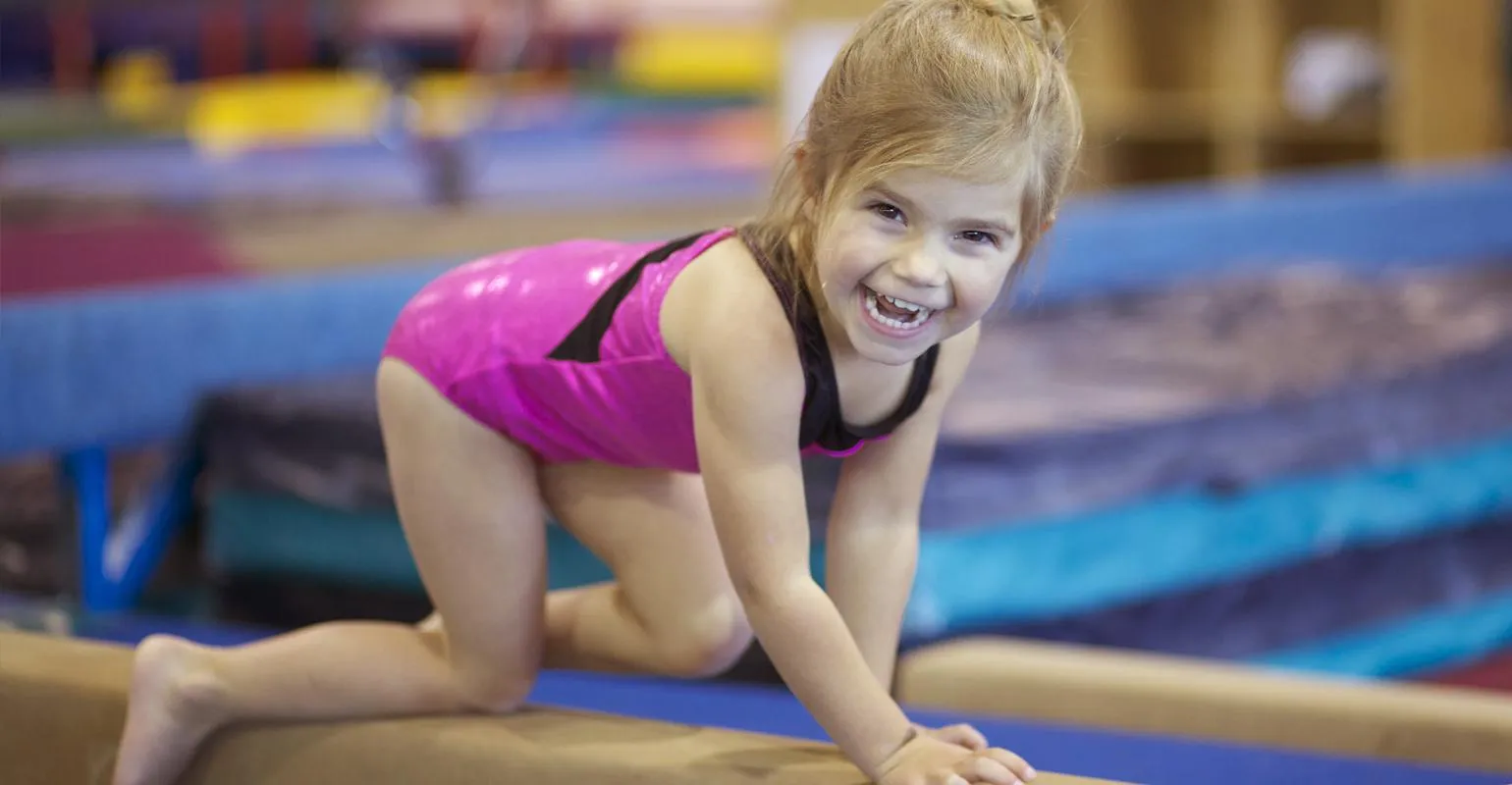 Preschool gymnast practicing on a low balance beam at EGA